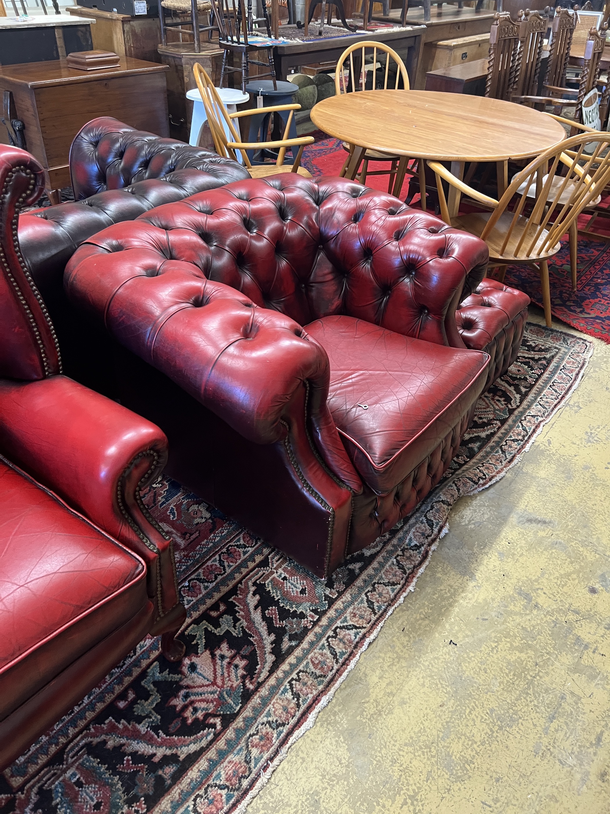 A Thomas Lloyd buttoned burgundy leather Chesterfield sofa, length 200cm, depth 85cm, height 72cm, two leather armchairs and a footstool
